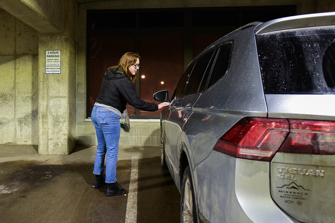 Carli Dewbre, with the Montana Bar Fairies, places a coffee card, thanking people for not drinking and driving, onto a car in Whitefish that was possibly left overnight. Dewbre's brother, Bobby, was struck and killed by a drunk driver last year. (Kate Heston/Daily Inter Lake)