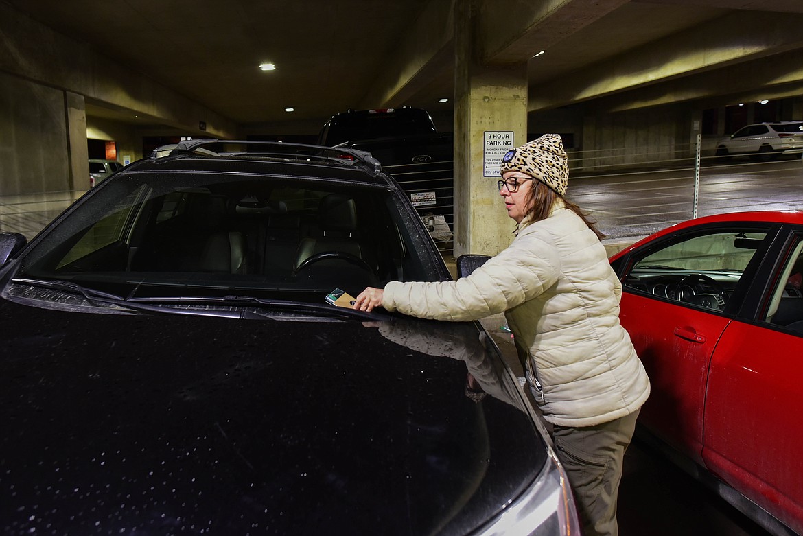 Beth McBride, with the Montana Bar Fairies, places a coffee card, thanking people for not drinking and driving, onto a car in Whitefish that was possibly left overnight. McBride's son, Bobby Dewbre, was struck and killed by a drunk driver last year. (Kate Heston/Daily Inter Lake)