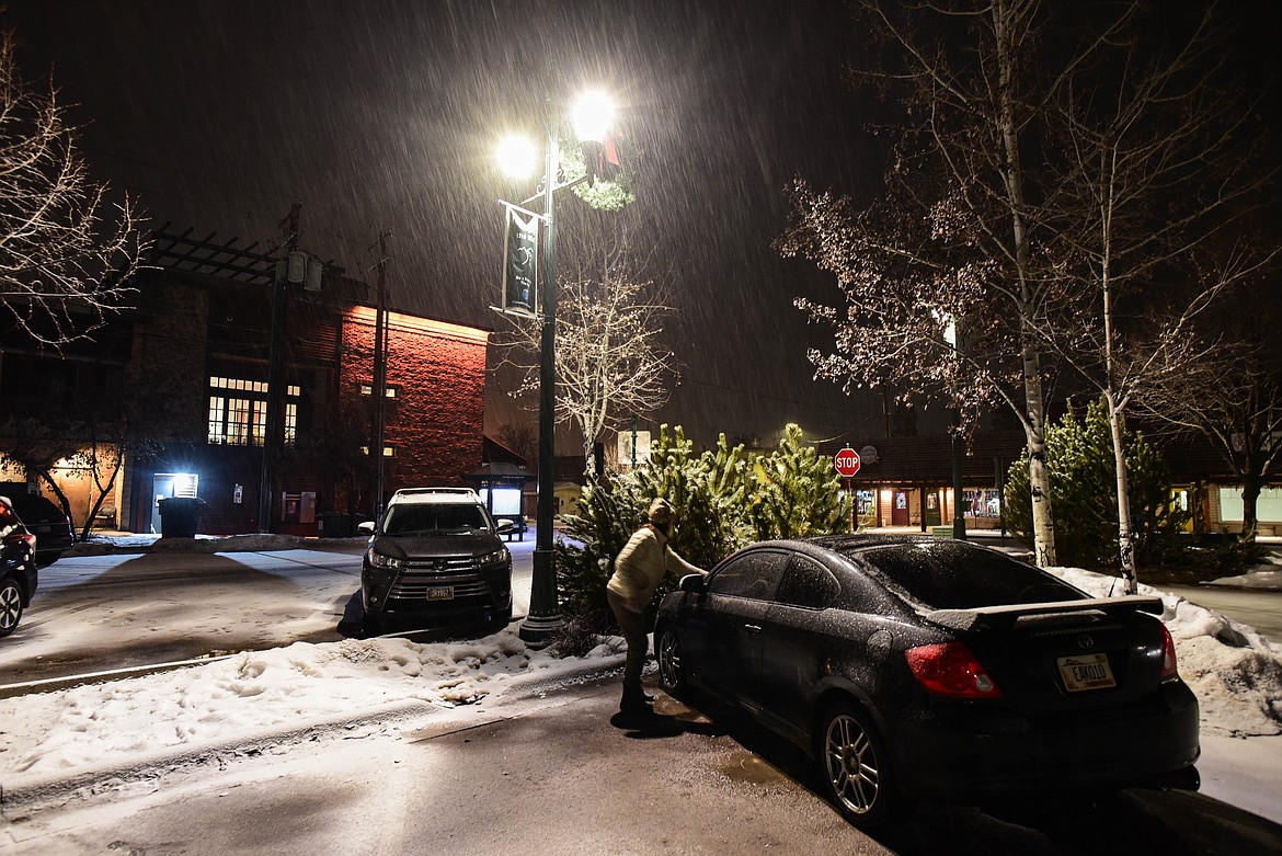 Beth McBride, with the Montana Bar Fairies, places a coffee card on a car possibly left overnight at a parking lot in downtown Whitefish on Feb. 4, 2024. McBride is the mother of Bobby Dewbre, who was struck and killed by a drunk driver last year. (Kate Heston/Daily Inter Lake)