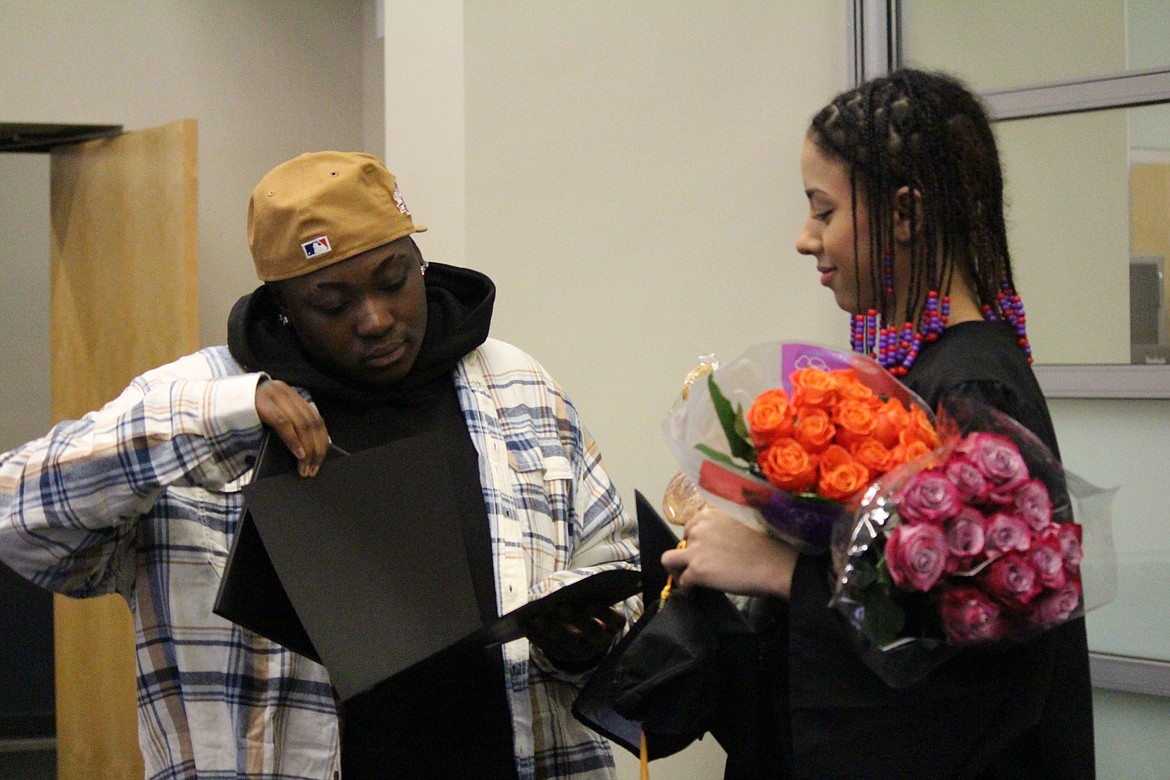 A family member checks out the GED and diploma earned by Monica Ford, right, after Open Doors graduation ceremonies Thursday.