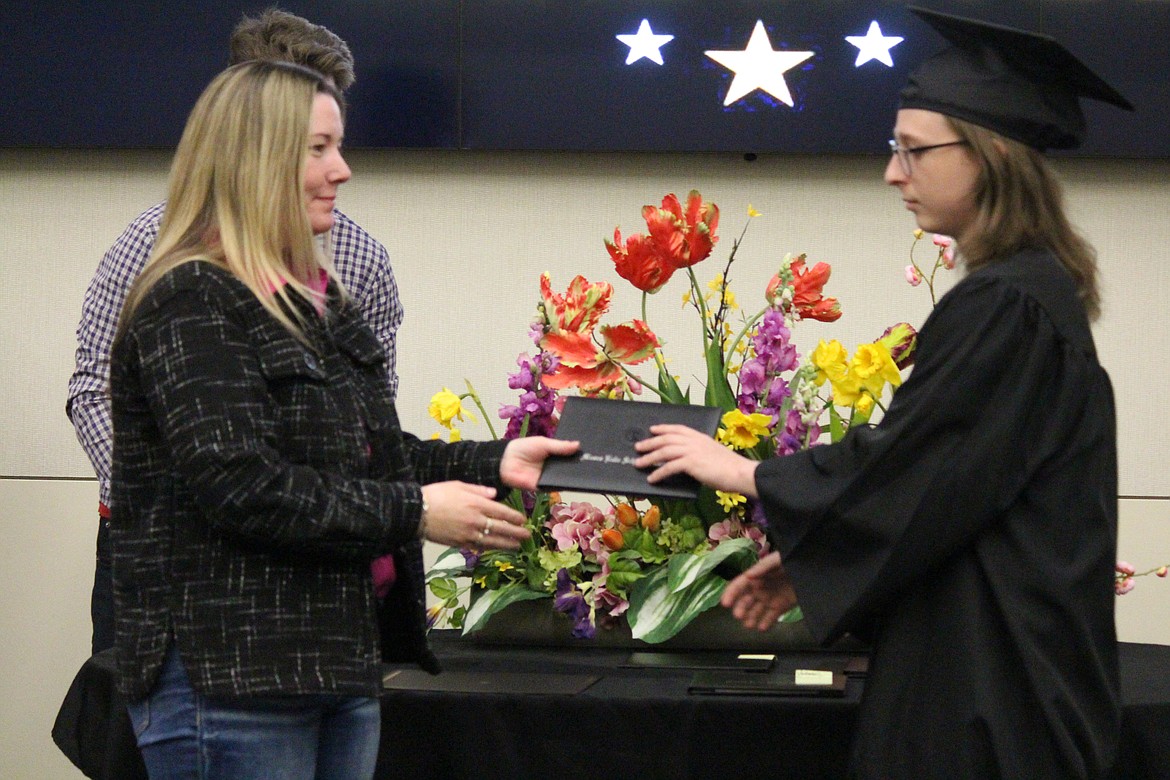 Kyler Neer-Orton, right, is handed his diploma by Moses Lake School Board member Carla Urias, left.