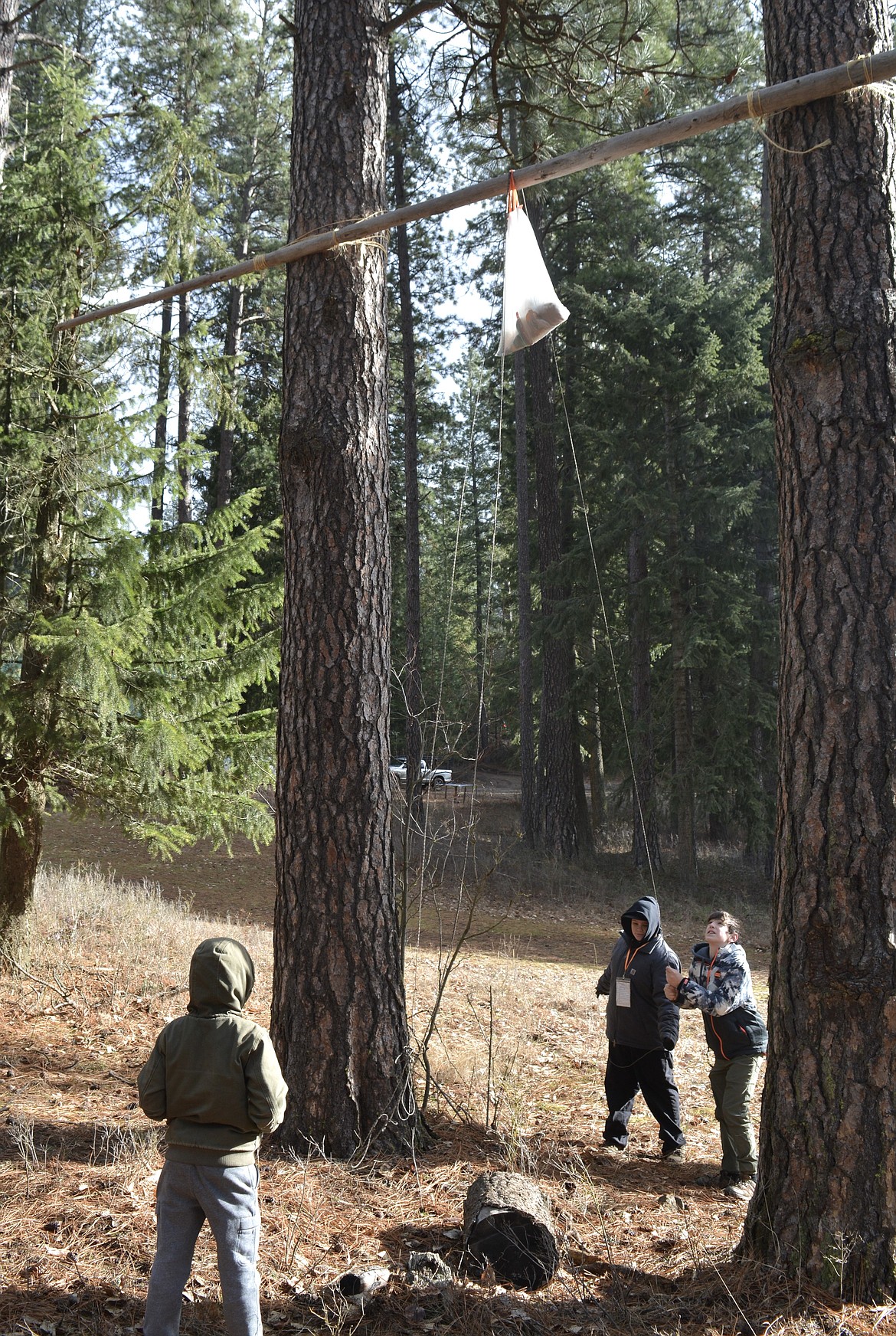 Jaxson Schwartz and Cole Anderson adjust the height of their bear bag so that squirrels are less likely to break into their supplies. Keeping food and items with strong odors up in a tree away from camp is an important survival tactic to avoid bear encounters.