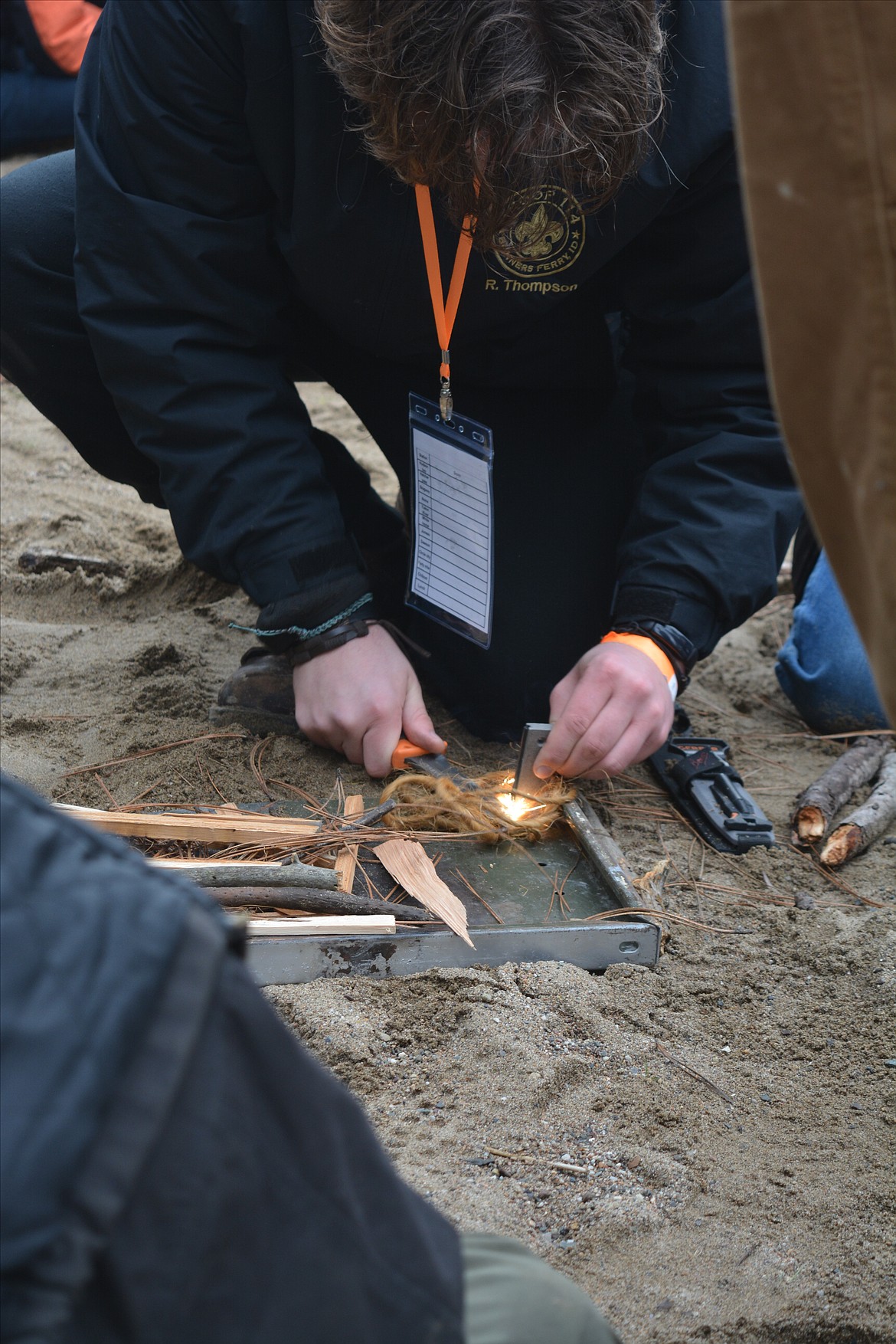 Riley Thompson ignites the twine at a fire-making station on the shoreline.