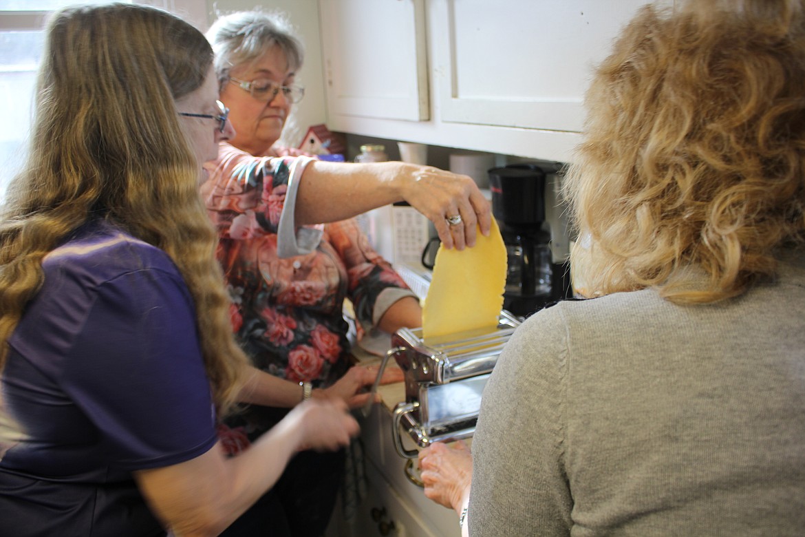 The Monday Confab at the Mineral County Library was a class on making pasta from scratch. Instructor Deb Kelsey holds and loads the dough into the pasta machine while Gala Rice cranks and Loie Turner catches. Monday Confabs are free to attend, and everyone is welcome. (Monte Turner/Mineral Independent)