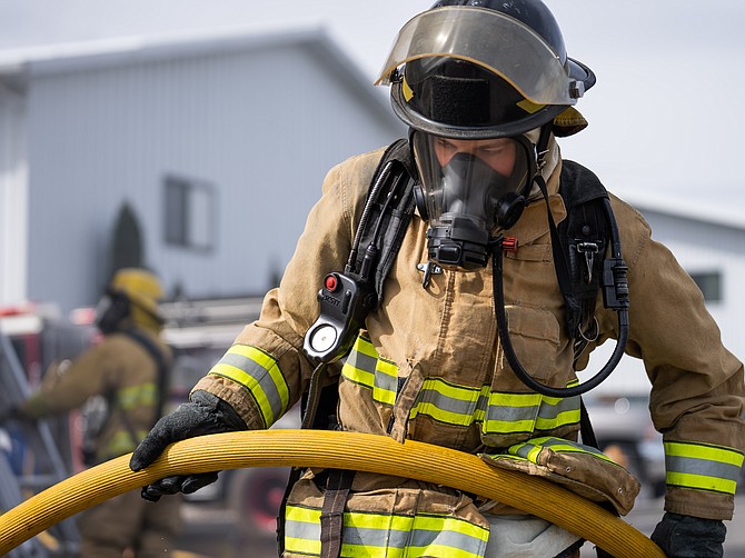 A North Idaho College Firefighter 1 Academy student pulls a hose during a training burn at the city of Coeur d’Alene Fire Station No. 2.