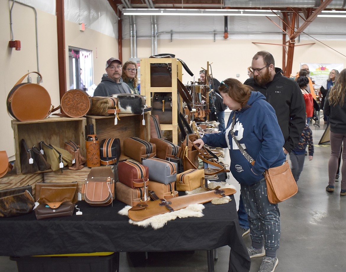 Sheena Cameron, left, and James Allen check out a potential laptop bag at Roy’s Custom Leather Work & Repair’s booth at the Valentine’s Market Saturday.