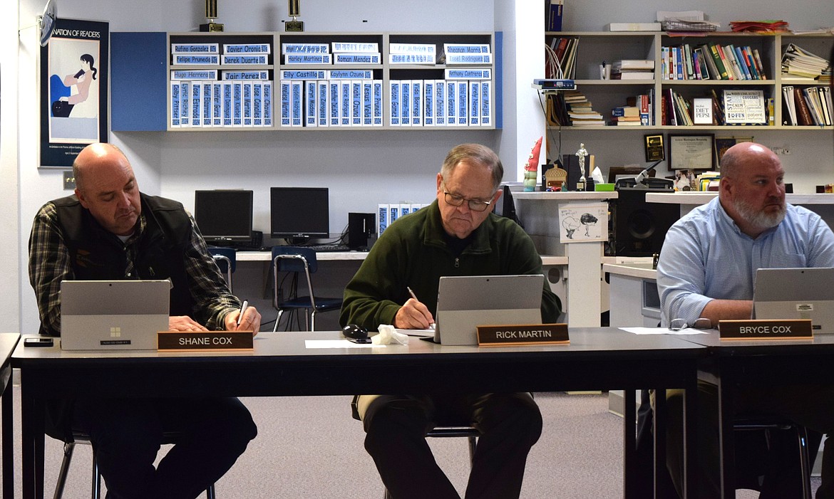 From left: Warden School Board members Shane Cox, Rick Martin and Bryce Cox take notes and discuss the school district’s increasing enrollment during Thursday evening’s regular meeting at Warden High School’s library.