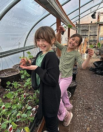 Hayden Meadows Elementary fourth graders Blakelee Griffits, left, and Reese Bligh are happy in the greenhouse Tuesday as they prepare for spring planting.