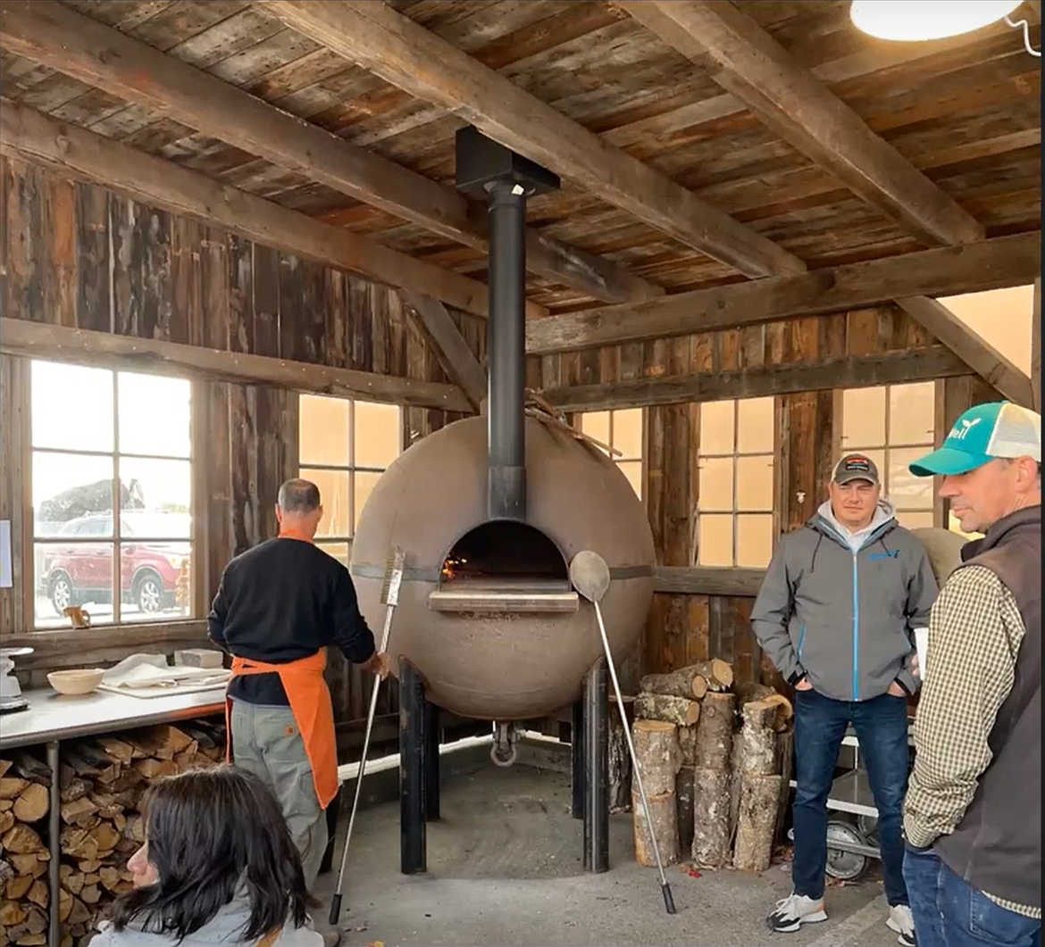 A pizza oven crafted from converted WWII anti-submarine net buoy served as a source of solace as farmers gathered at the Washington State University Bread Lab in Skagit County in 2022. Community members have come together to replicate the project in Rigby, Idaho.