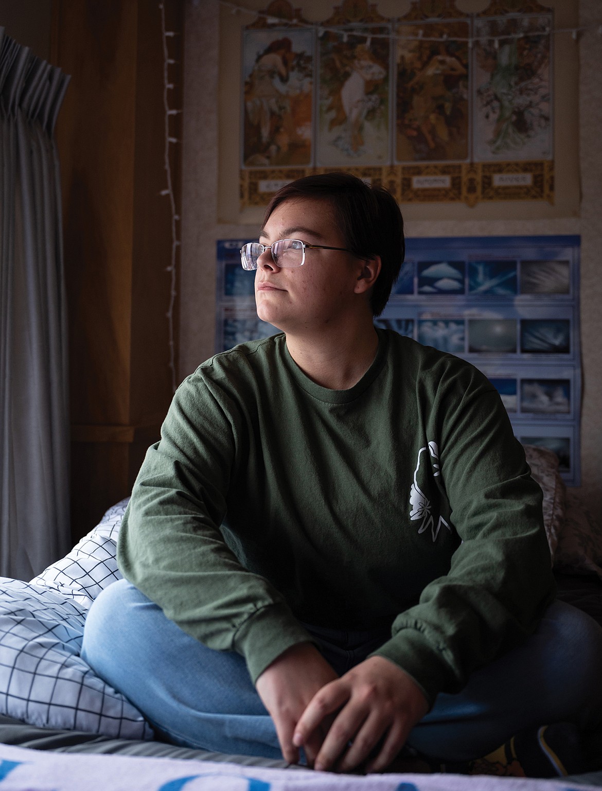 Josie Libby sits on her dorm room bed and glances out of her window that overlooks the University of Montana’s campus. (Ava Rosvold/UM Byline Magazine)