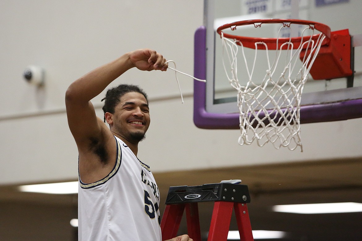 MLCA/CCS senior Caleb Jones cuts down part of the net at Thursday’s Central Washington 1B district title game in Wenatchee. The Lions defeated Soap Lake 78-45.