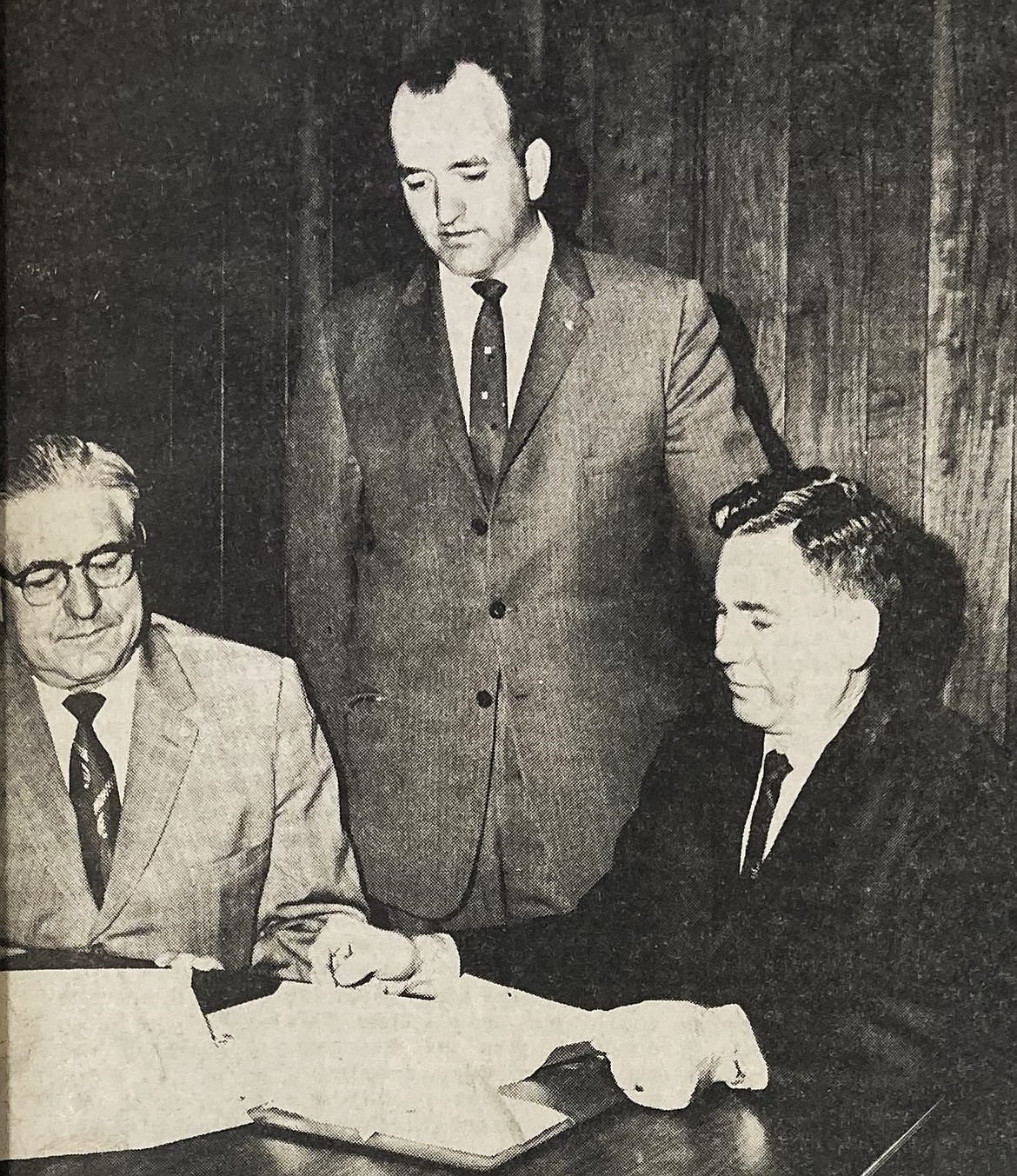 Kennedy Commission officers L.L. Gardner (seated, left), James McKinnon (right) and John Hunt consider ways to honor JFK.