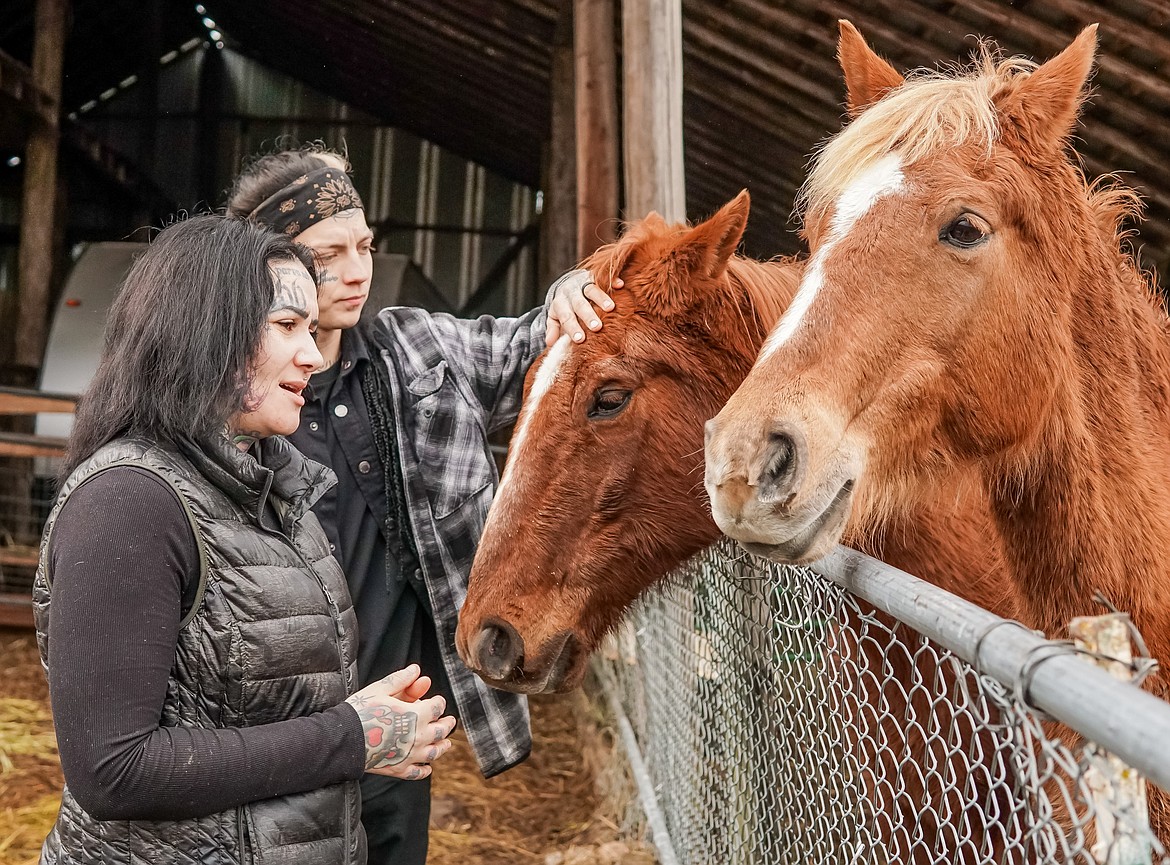 Samantha and Kyler Elliott stand with horses Kaw Liga and Daisy after giving them some morning treats Feb. 21.
