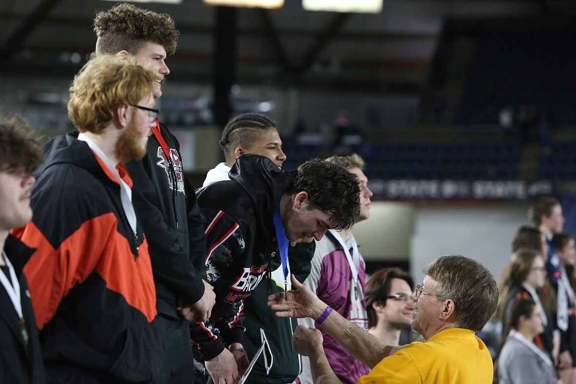 Lind-Ritzville/Sprague senior Gabe Smith, bending, earns his first-place medals on the podium at the Tacoma Dome.