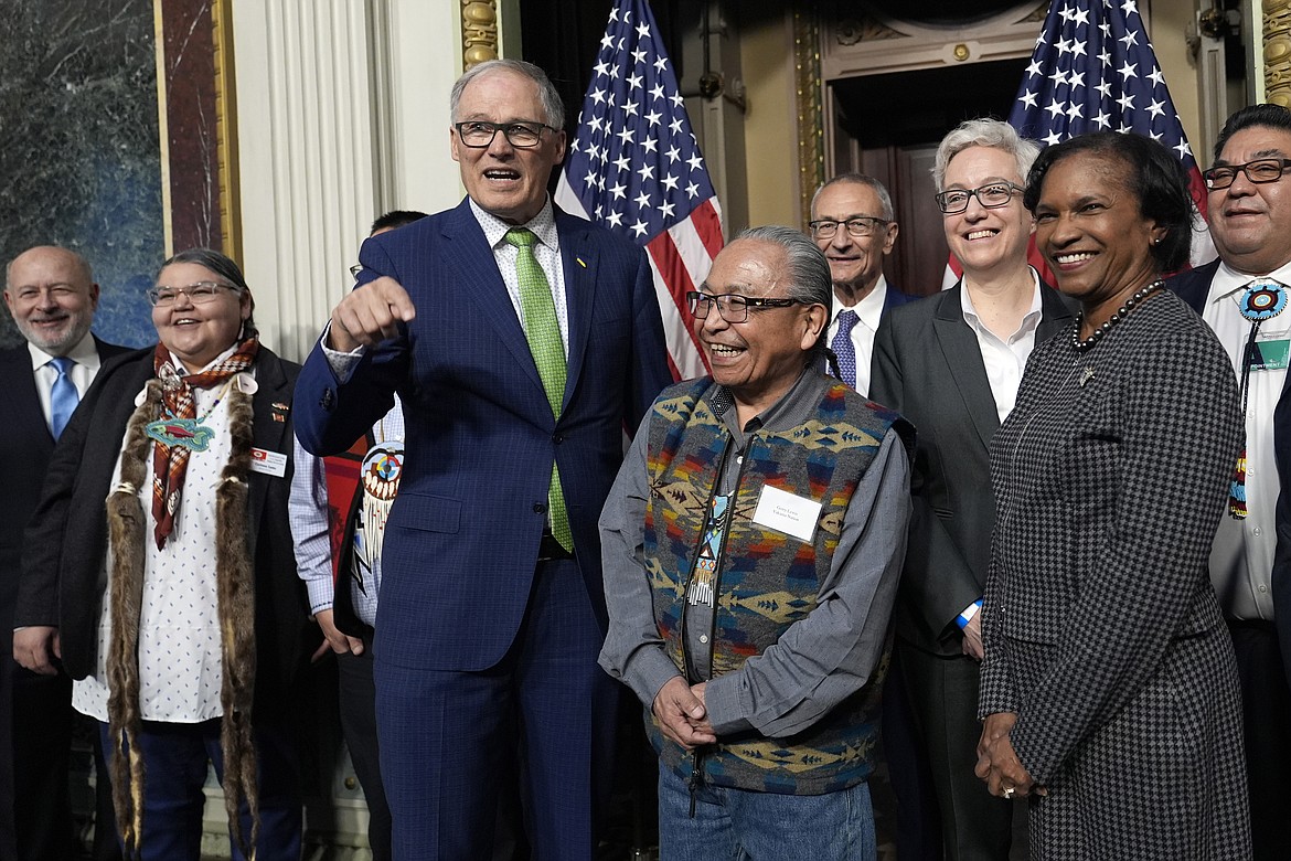 Washington Gov. Jay Inslee, third from left, stands with Chair Gerry Lewis of the Yakama Nation, fourth from left, as they and others pose for a photo following a ceremonial signing ceremony in Washington, Friday, Feb. 23, 2024. (AP Photo/Susan Walsh)