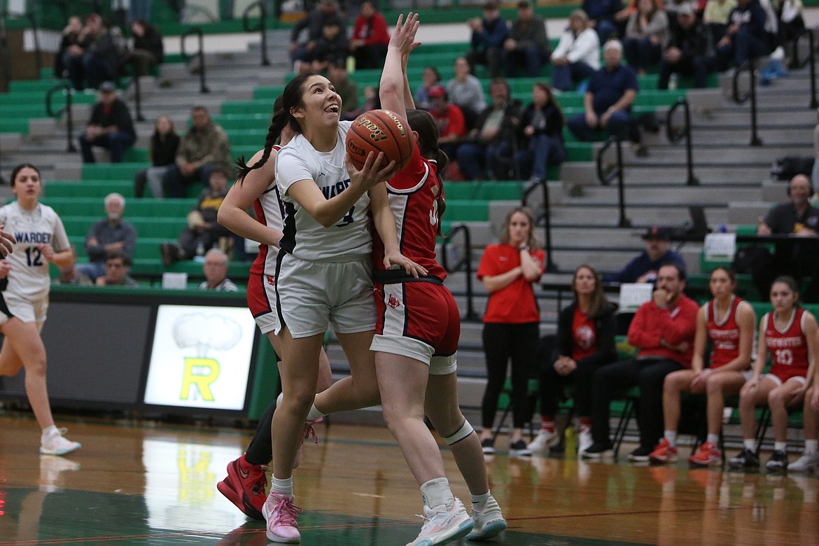 Warden freshman Angelina Buck, in white, keeps her eye on the rim while attempting a lay-up in the first quarter against Brewster.