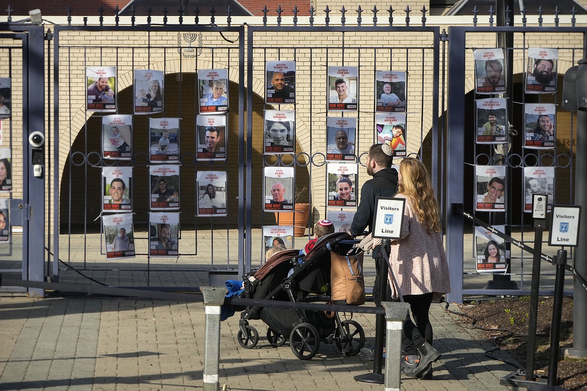 A family walks up to the entrance of the Israeli Embassy, Monday, Feb. 26, 2024, in Washington. An active-duty member of the U.S. Air Force has died after he set himself ablaze outside the Israeli Embassy in Washington, D.C., while declaring that he "will no longer be complicit in genocide." (AP Photo/Mark Schiefelbein)