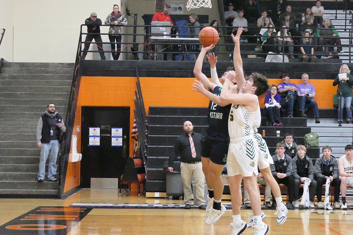 St. Regis junior forward Kaden Sanders (15, white) blocks a shot by Manhattan Christian's Will Rufatto during their semi-final game at the Western Divisional C basketball tournament in Frenchtown this past Friday.  (Chuck Bandel/VP-MI)