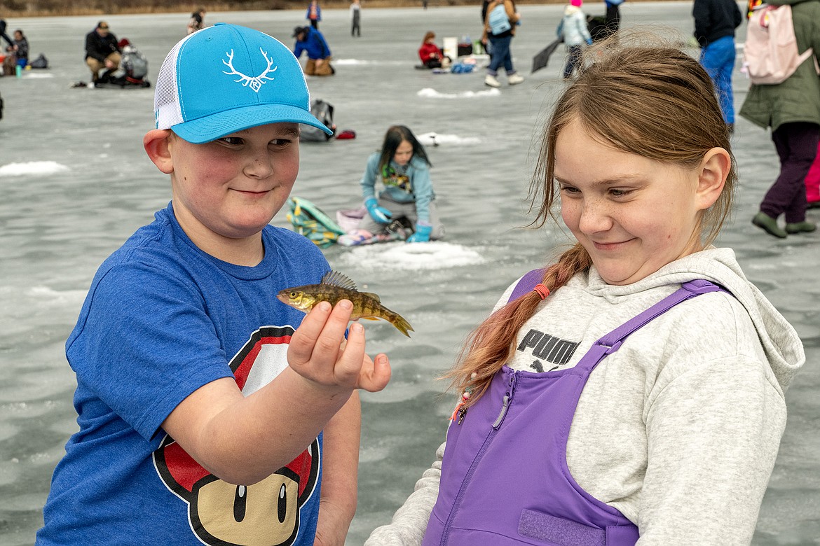 Lillialla Benner (right) politely declines to kiss the fish she caught on Murphy Lake Thursday as Max Flickinger helps her release it. (Avery Howe photo)