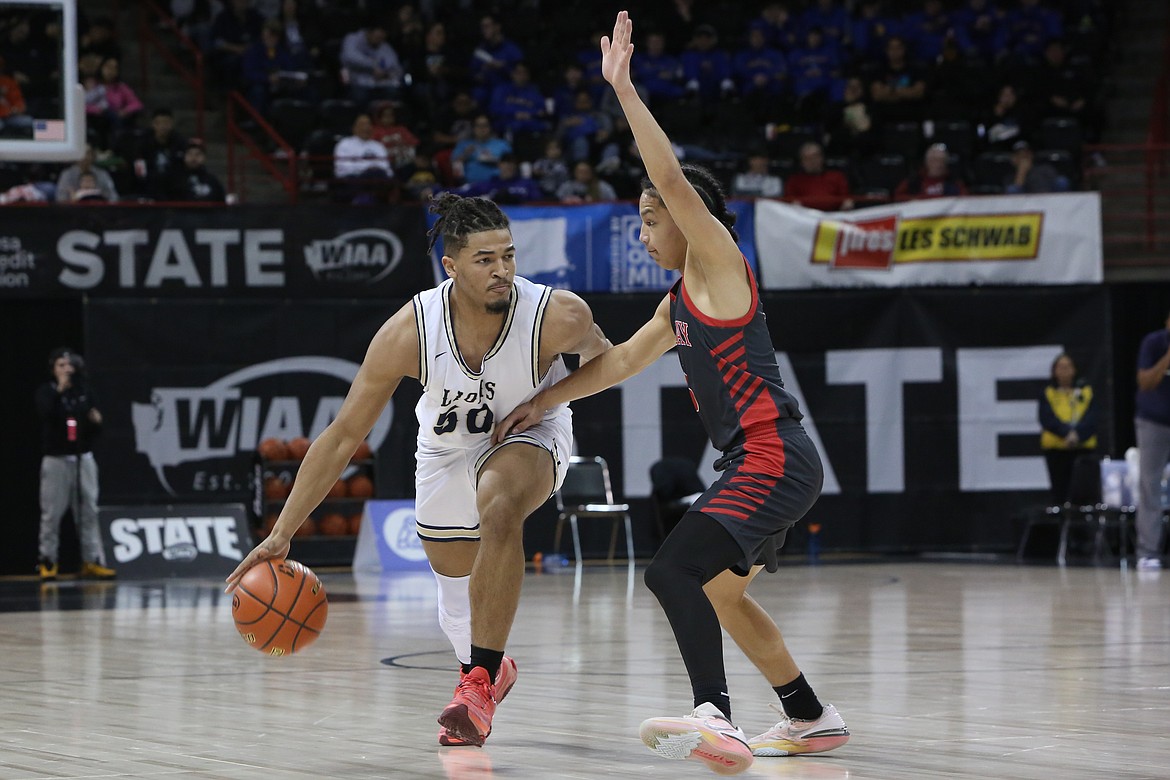 MLCA/CCS senior Caleb Jones, left, dribbles the ball in the frontcourt against Neah Bay Thursday at the Spokane Arena.