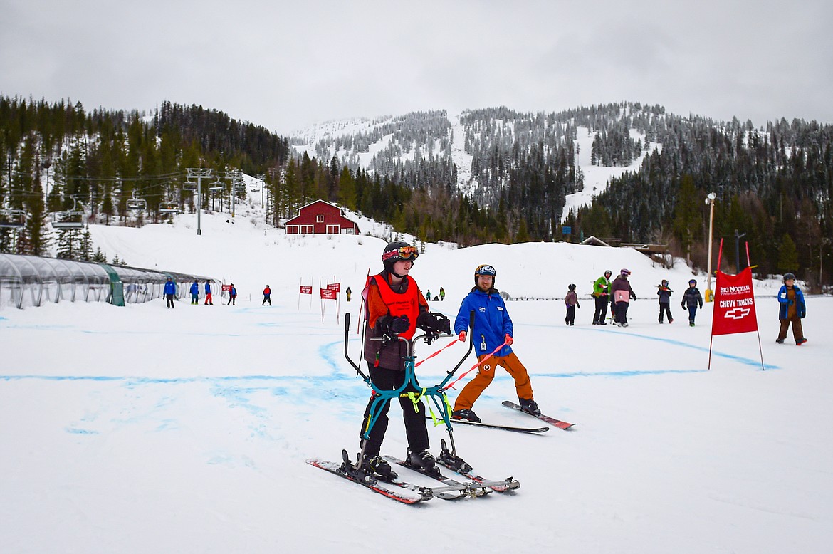 Alaina Murr, with the Whitefish Bulldogs team, crosses the finish line in the Alpine Glide event with Dream Adaptive Program Staff Johnny Middleton during the Special Olympics Montana Glacier Area Winter Games at Whitefish Mountain Resort on Thursday, Feb. 29. (Casey Kreider/Daily Inter Lake)b