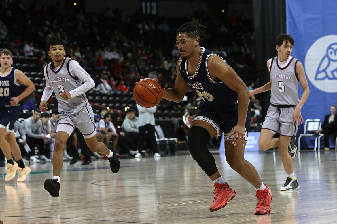 MLCA/CCS senior Caleb Jones, in blue, dribbles the ball down the floor against Lummi Nation. Jones is one of two Lion seniors, joined by senior Jonah Robertson.