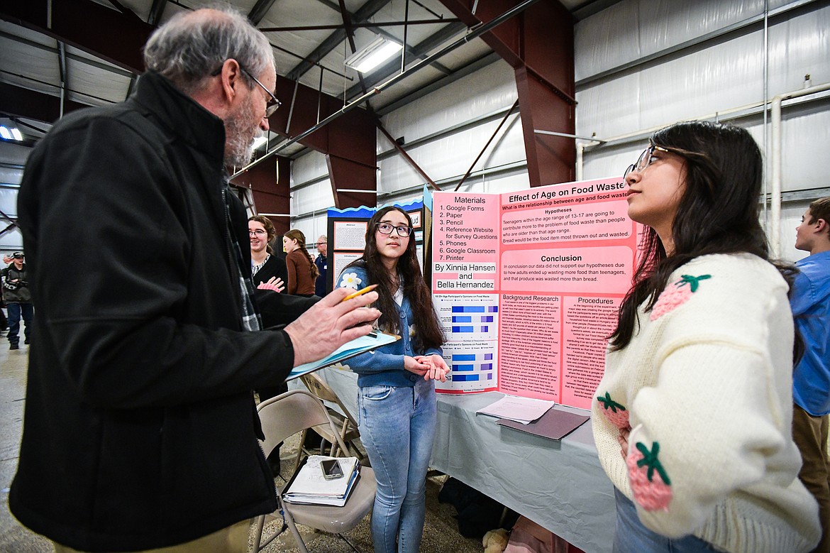 Flathead High School freshmen Xinnia Hansen, center, and Bella Hernandez, right, listen to feedback from a judge as they describe their project titled "Effect of Age on Food Waste" at the Flathead County Science Fair at the Flathead County Fairgrounds Expo Building on Thursday, March 7. (Casey Kreider/Daily Inter Lake)