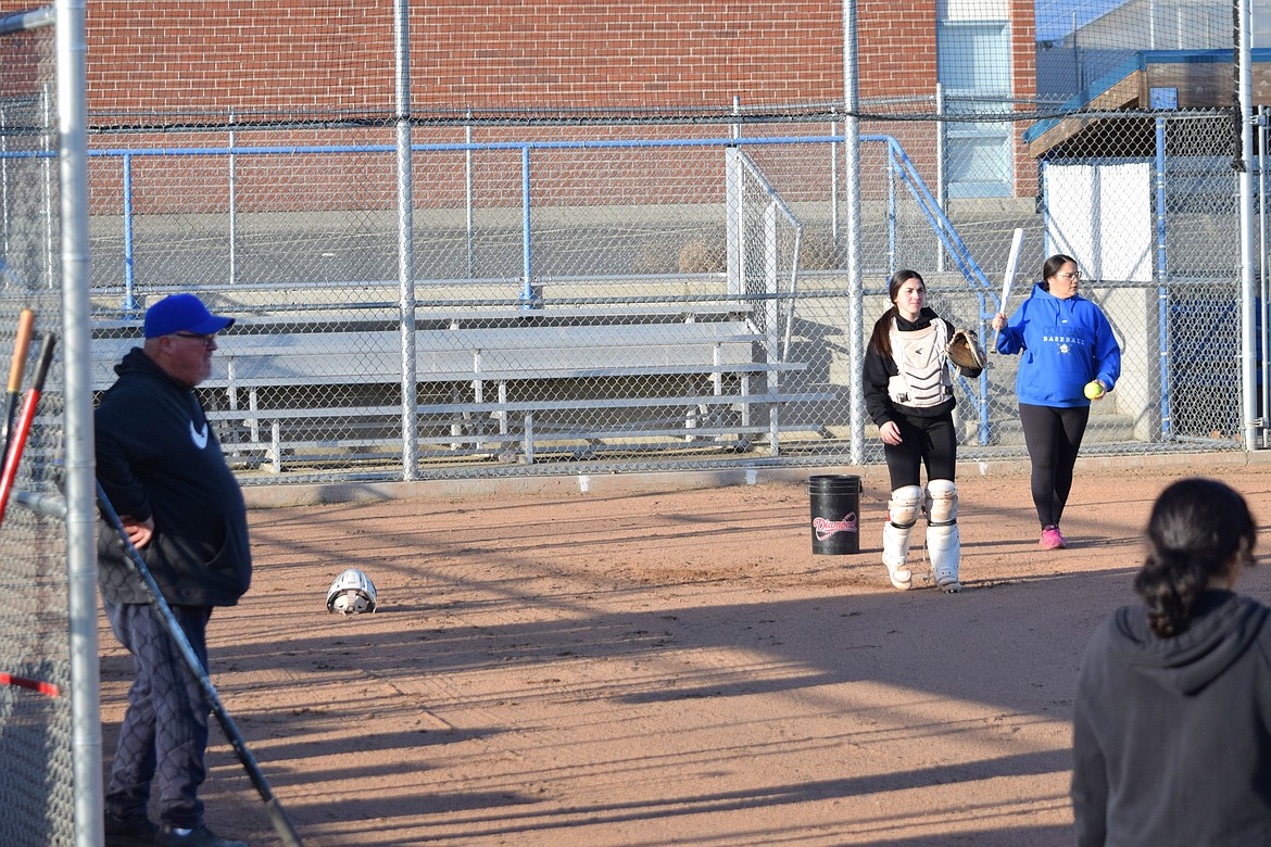 Warden Softball Head Coach Randy Wright, left, watches as Warden High School Varsity players practice pitching and batting on the diamond behind the high school.