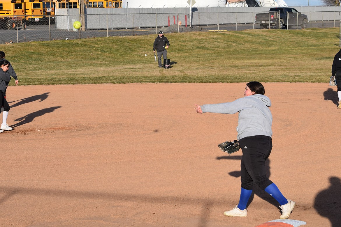 A player standing on first base throws the ball during Warden High School Softball practice.