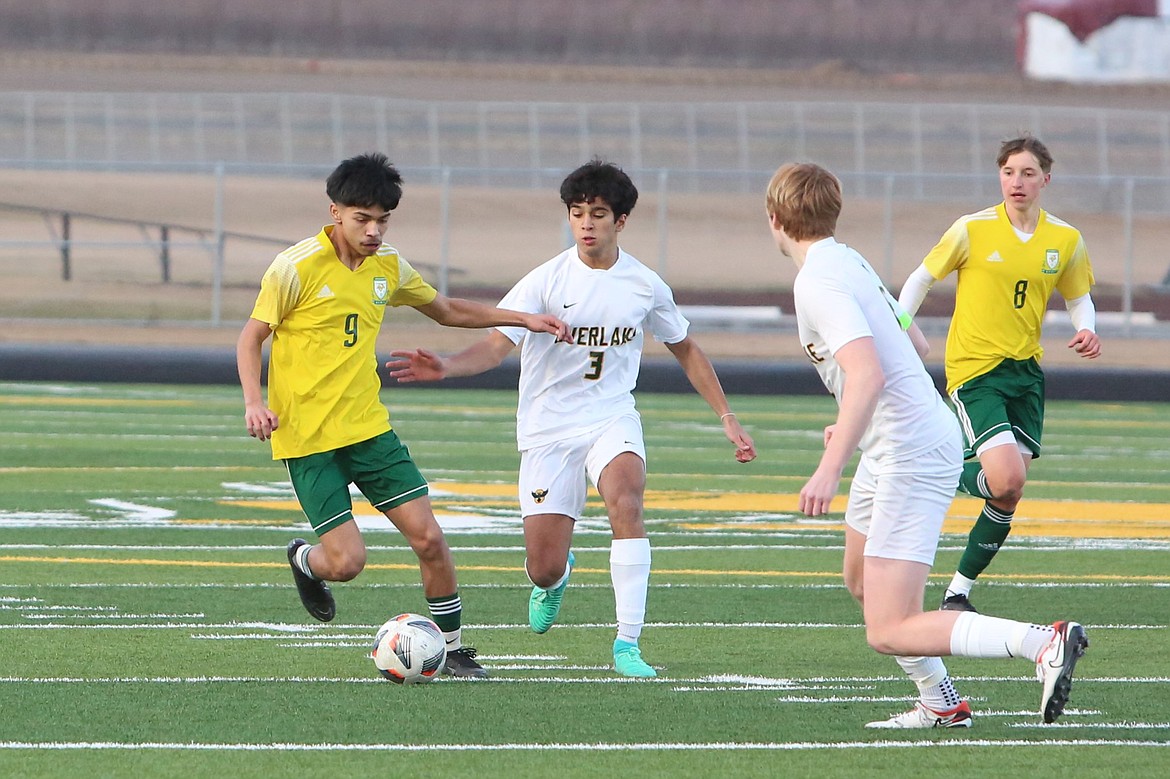 Quincy sophomore Ken Morales (9) keeps his eyes on the ball while trying to get past a pair of Overlake defenders.