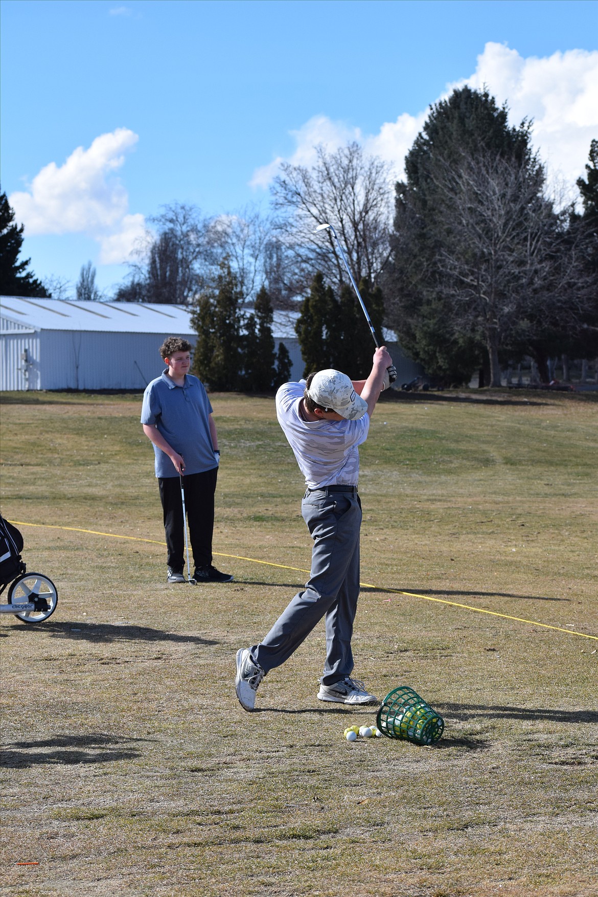 Caleb Moberg maintains his focus on the ball as he swings at the driving range.