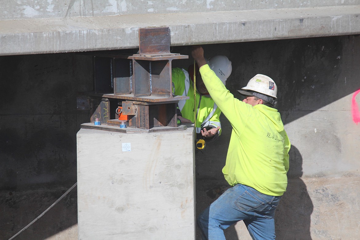 Construction workers from N.A. Degerstrom check the measurements on the temporary supports for Bridge 202, currently under repair.