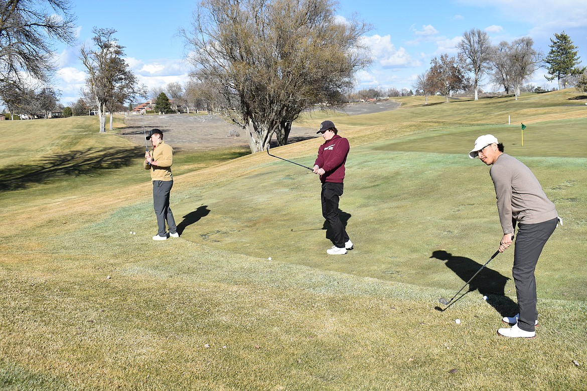 From left: Moses Lake High School golfers Christian Mathis, Mason Bradford and Isaiah Patino practice their chipping at the Moses Lake Golf & Country Club Tuesday.