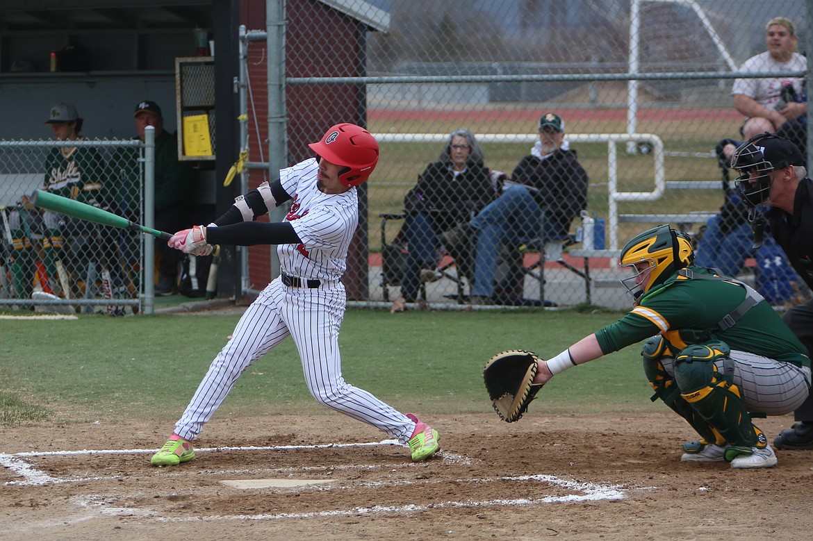 Othello junior Kal-El Ozuna, in white, records a hit in the bottom of the first inning of Monday’s game against Shadle Park.