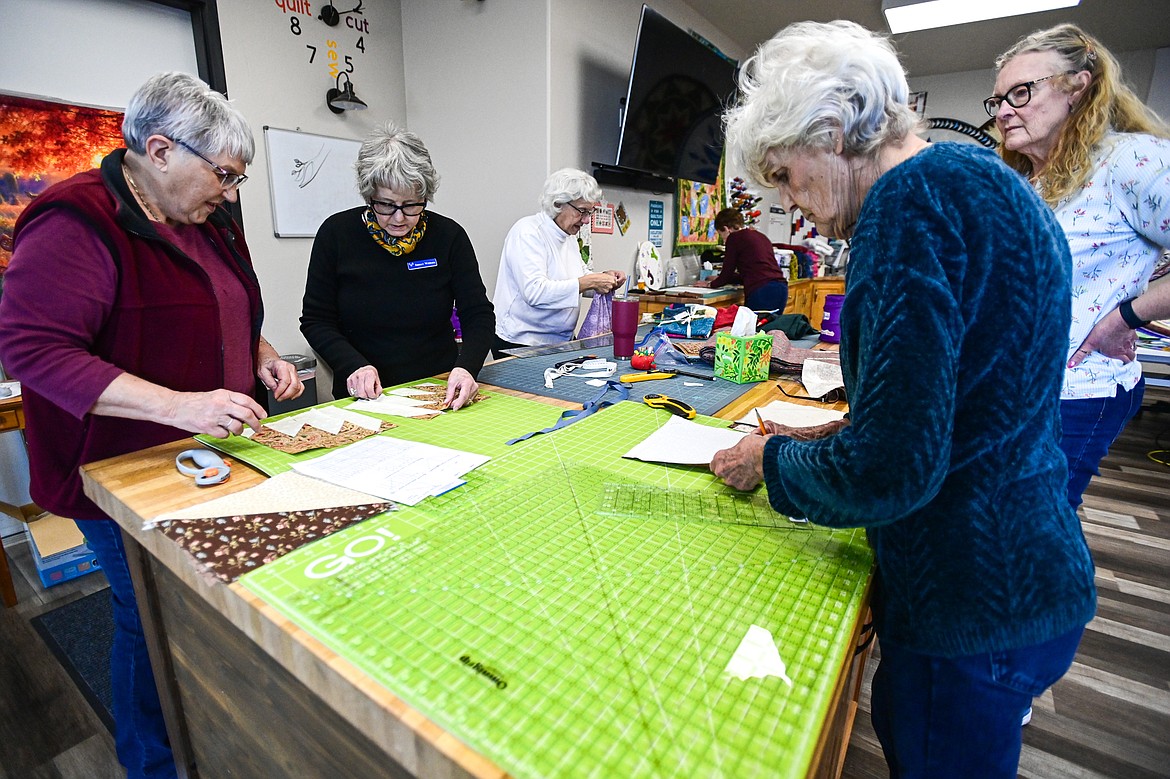 Nancy Richwine, left, gives a few pointers about how to stitch mountains for a Delectable Mountains quilt to Shelly Withall, Adelyn Moss and Valerie Peters during a Flathead Quilters' Guild sewing day at the Quilt Gallery in Kalispell on Wednesday, March 13. (Casey Kreider/Daily Inter Lake)