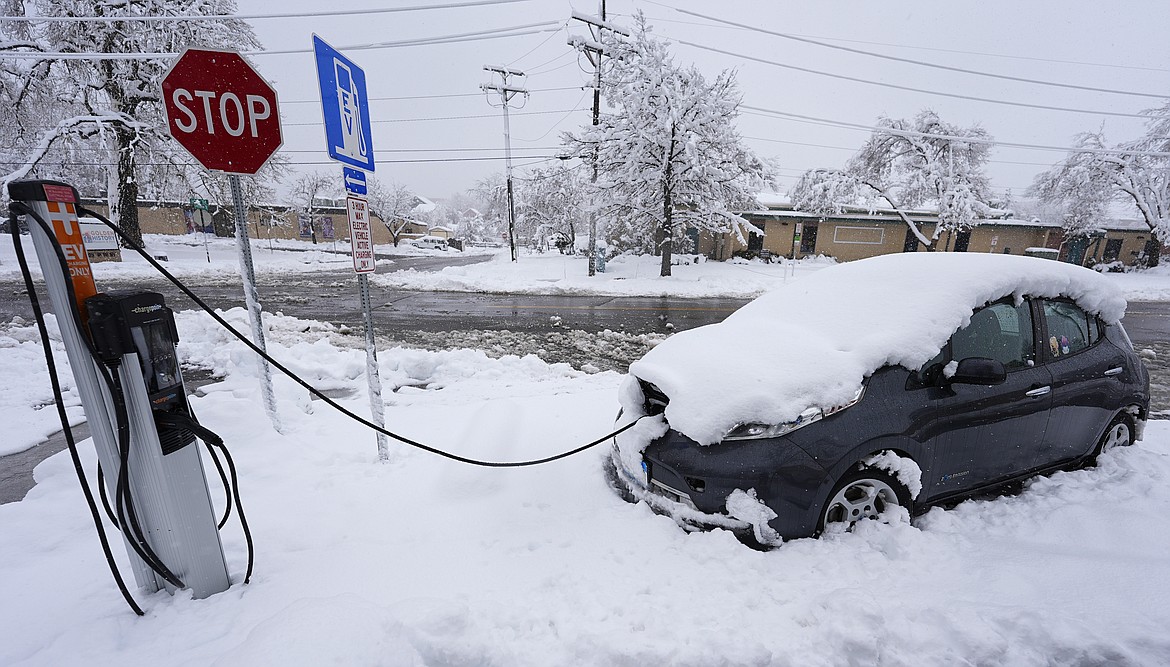 An electric Nissan Leaf gets a charge at a station as a late winter storm dropped up to a foot of snow Thursday, March 14, 2024, in Golden, Colo. Forecasters predict that the storm will persist until early Friday, snarling traffic along Colorado's Front Range communities. (AP Photo/David Zalubowski)