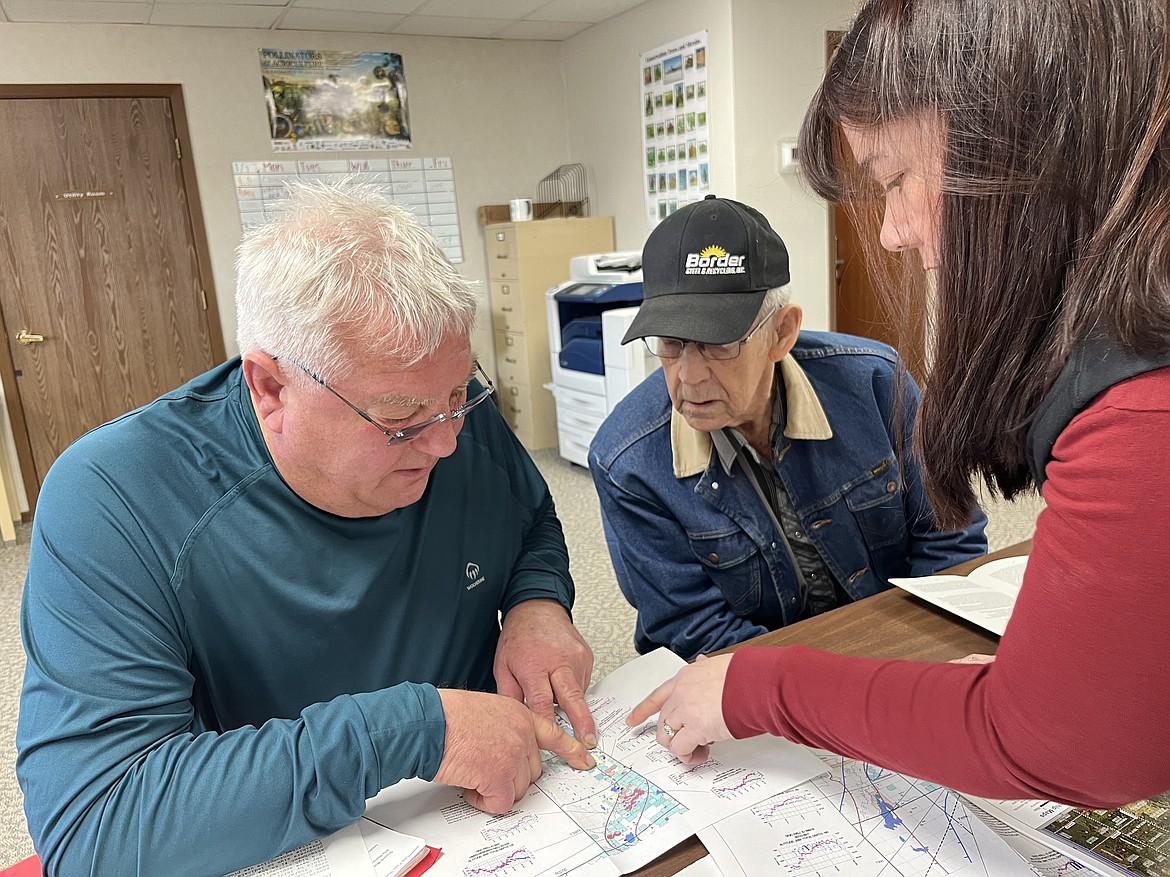 From left to right, Jeff Wivholm, Marlowe Onstead and Amy Yoder look through maps of irrigation pivots and aquifer allocations inside the Sheridan County Conservation District office in Plentywood. (Photo courtesy Keely Larson)