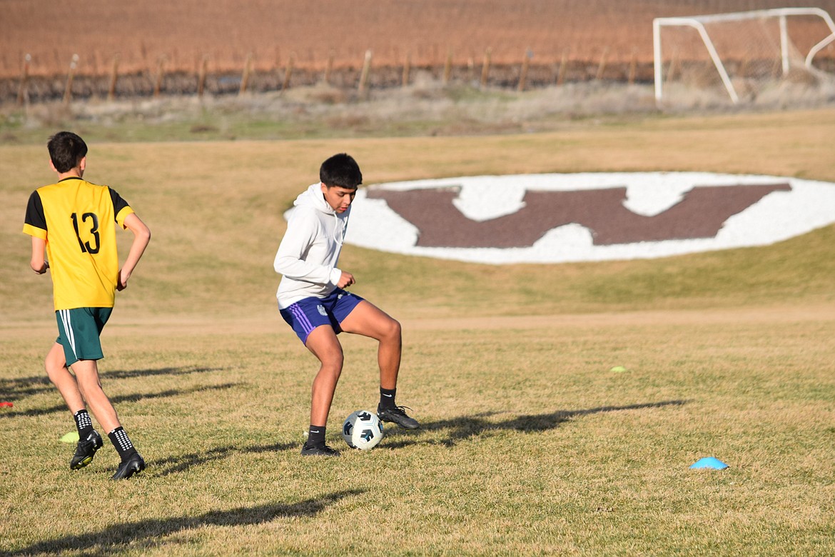 A Wahluke Boys Soccer player dribbles the ball during practice in front of a large “W” on the Wahluke High School soccer field March 4.
