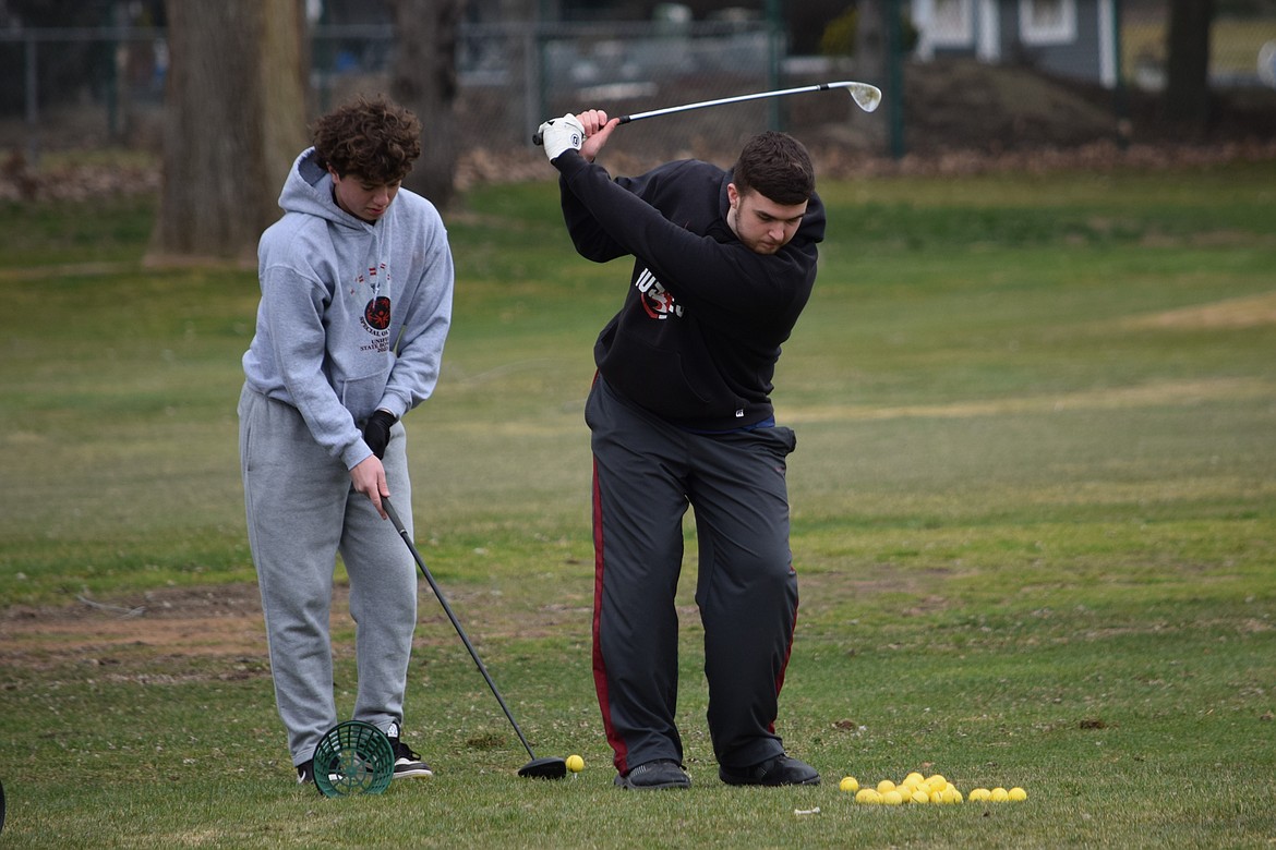 Othello Boys Golf player Ajay Parrish, right, practices with other team members at the driving range at Othello Golf Club Monday evening. Head Coach Trevor Salsbury said Parrish is likely his number one player this season.