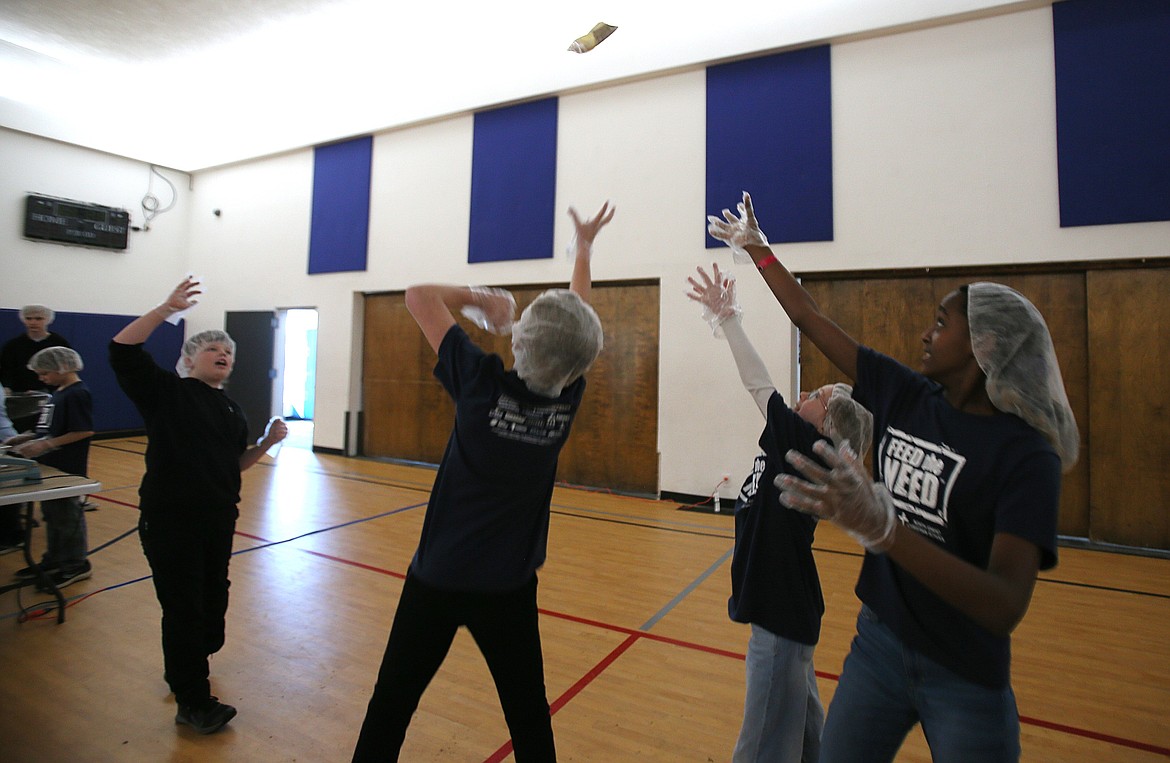 A packaged meal is ready to be boxed as Kanin Leard, left, tosses it into the air to be caught by his fellow North Idaho Christian School sixth graders Kowen Lawhead, center, Rhema Buck, center right, and Hana Gallegos, right, March 14 during the Feed the Need packing event.