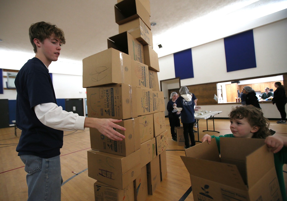 Junior James Deschryber assists 4-year-old Jack Thomas with building a box tower March 14 during the Feed the Need packing party at North Idaho Christian School in Hayden.