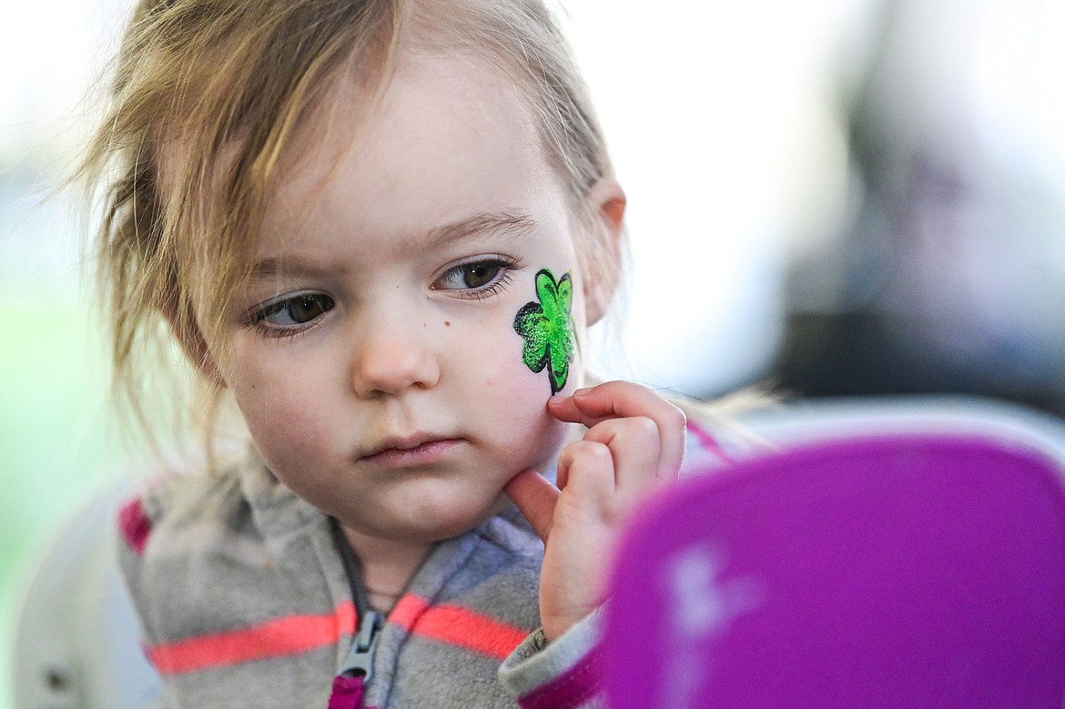 Bailey Peterson looks at the shamrock painted on her cheek in the kids carnival area at Cloverfest in Columbia Falls on Saturday, March 16. (Casey Kreider/Daily Inter Lake)