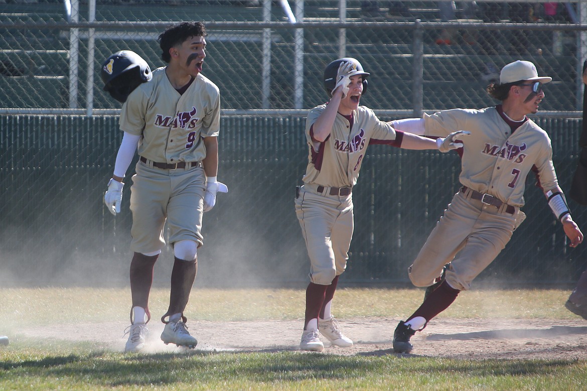 Moses Lake junior Jackson Carlos (9), senior Jayce Stuart (8) and sophomore Noah Hernandez celebrate at home plate after Carlos scores a game-winning run in the bottom of the eighth inning against Chiawana.