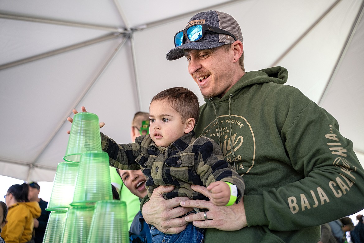 Bryan Helmbrecht (right) helps three-year-old Malakai Helmbrecht place the last cup on his tower at Culturefest on Satruday, March 16. (Avery Howe photo)