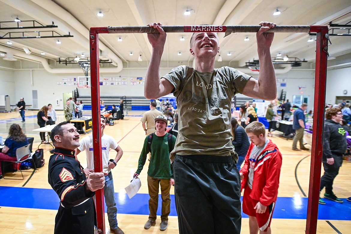 Bigfork High School junior Ty Anderson does pull-ups at the United States Marine Corps station with Staff Sgt. Ryan Steward at the Bigfork Job Fair at Bigfork High School on Wednesday, March 20. (Casey Kreider/Daily Inter Lake)
