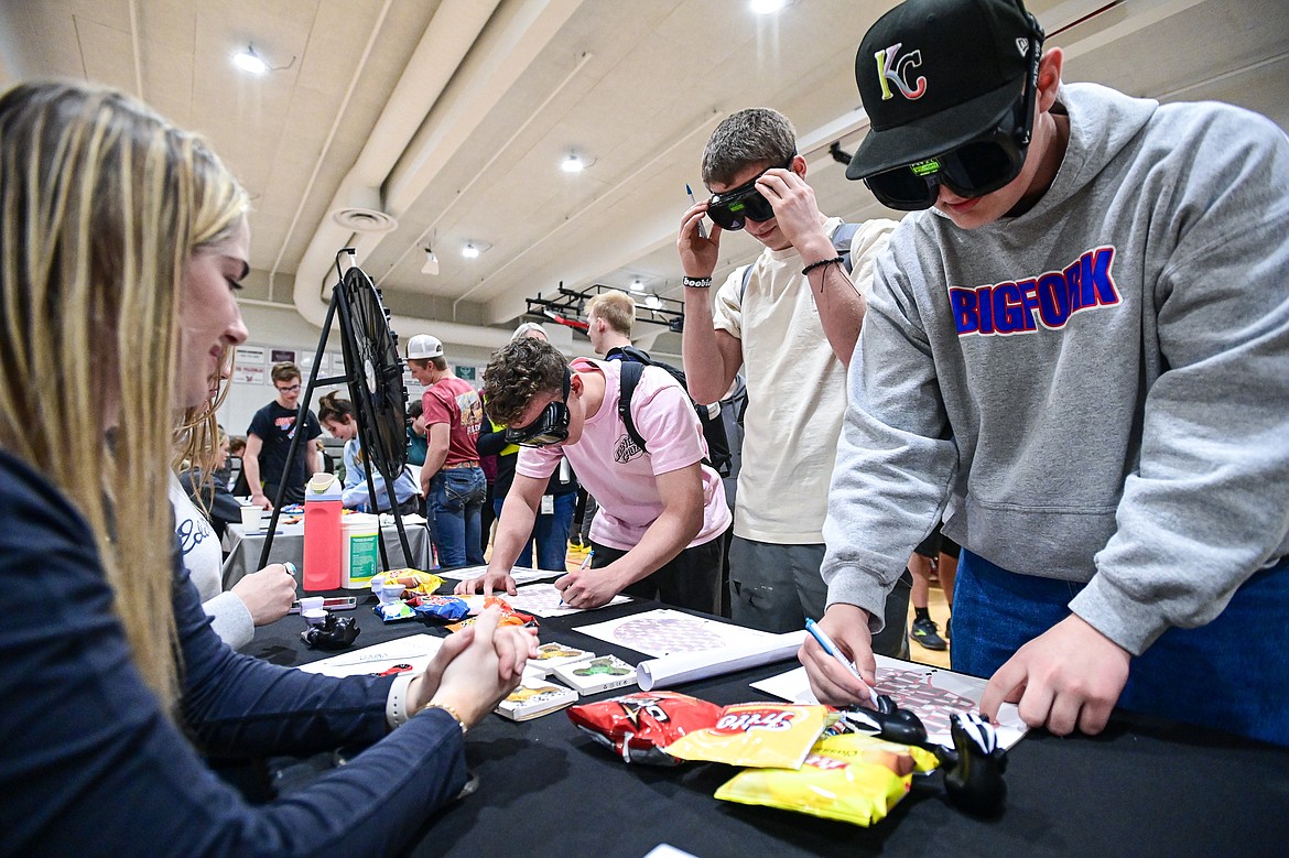 Bigfork High School students navigate their way through paper mazes while wearing Fatal Vision impairment goggles at the Flathead County Health Department stand at the Bigfork Job Fair at Bigfork High School on Wednesday, March 20. (Casey Kreider/Daily Inter Lake)
