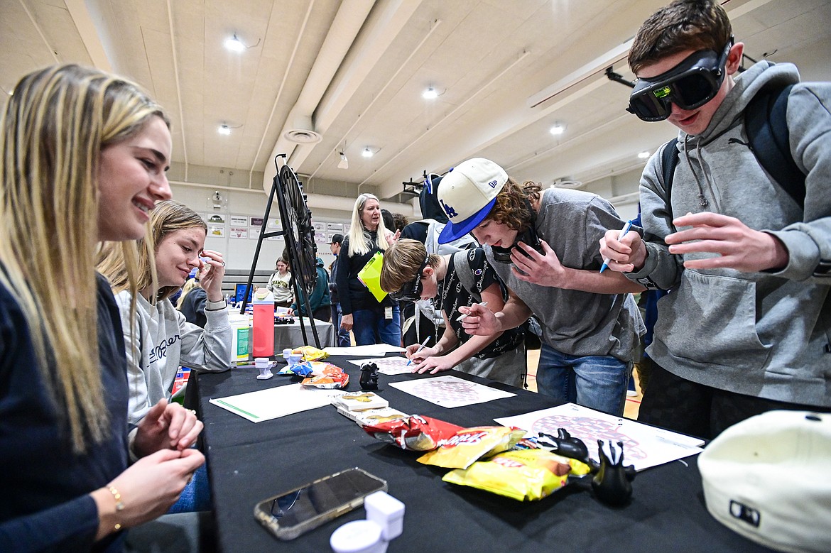 Bigfork High School students navigate their way through paper mazes while wearing Fatal Vision impairment goggles at the Flathead County Health Department stand at the Bigfork Job Fair at Bigfork High School on Wednesday, March 20. (Casey Kreider/Daily Inter Lake)
