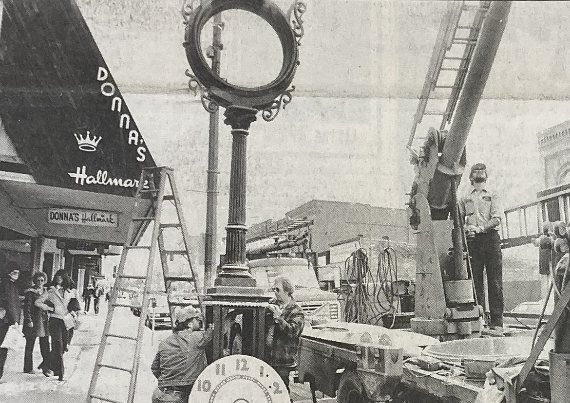 A work crew of, from left, Preston Rutherford, Bruce Dietrich and Dennis Baal reinstall the historic street clock in front of Clark’s Diamond Jewelers.