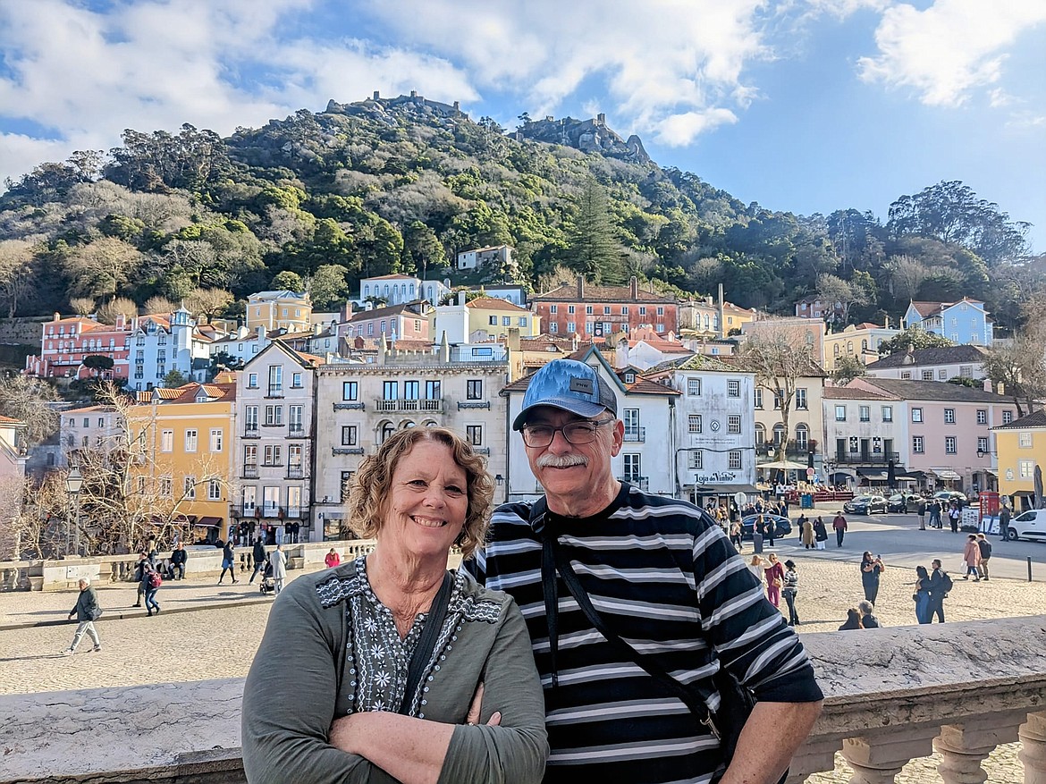 Dave and Brenda Oliveria stand in the National Palace at Sintra, Portugal, with a Moorish castle topping the mountain in the background.