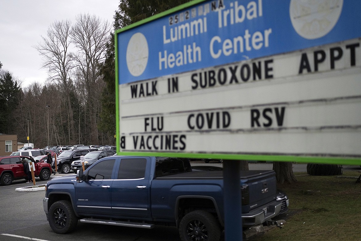 People walk through the parking lot of the Lummi Tribal Health Center advertising walk-in appointments for Suboxone, a medicine used to treat opioid dependence, on the Lummi Reservation, Feb. 8, 2024, near Bellingham, Wash. On Tuesday, March 20, 2024, Washington Gov. Jay Inslee has signed a multimillion-dollar measure to send state money to tribes and Indigenous people in the state who die from opioid overdoses at disproportionately high rates in Washington. (AP Photo/Lindsey Wasson, File)